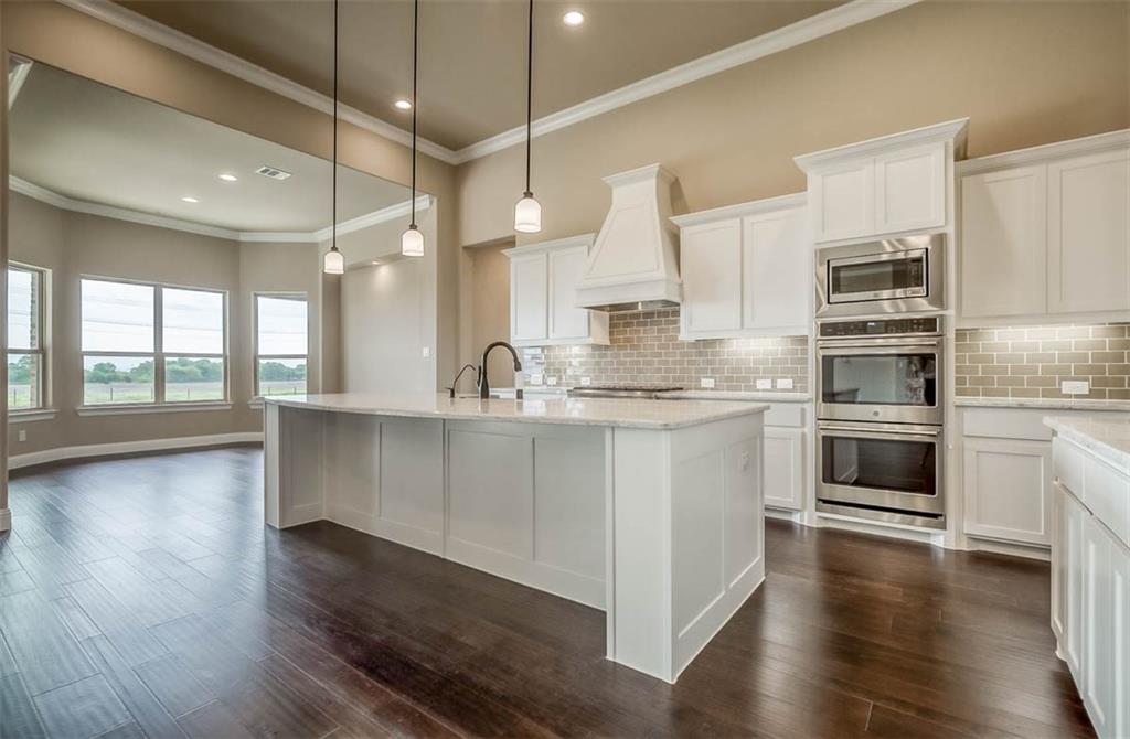 a kitchen with stainless steel appliances a stove a sink and white cabinets with wooden floors