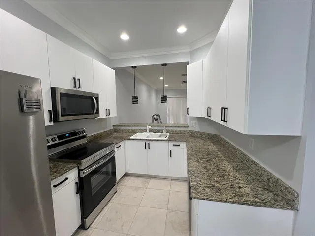 a large kitchen with granite countertop a sink and a stove top oven with wooden floor