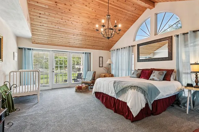 a spacious bedroom with a bed a chandelier and large window