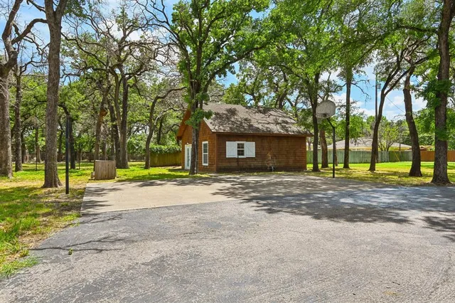 a view of a house with a big yard and large trees