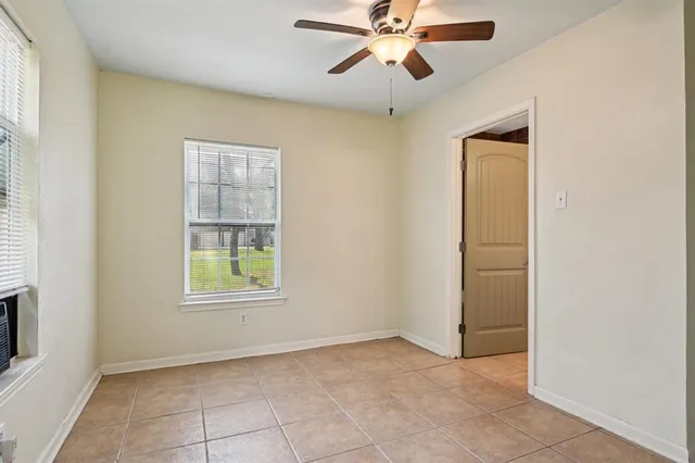 an empty room with windows and fan
