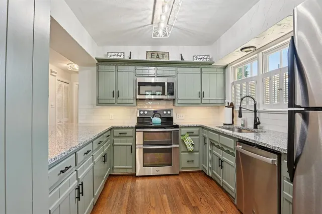 a kitchen with stainless steel appliances granite countertop a stove a sink and a microwave