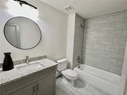 a bathroom with a granite countertop toilet a sink and a mirror
