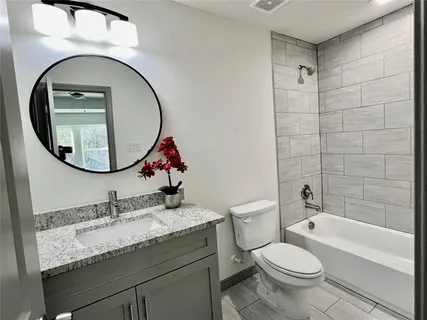 a bathroom with a granite countertop toilet a sink and a mirror