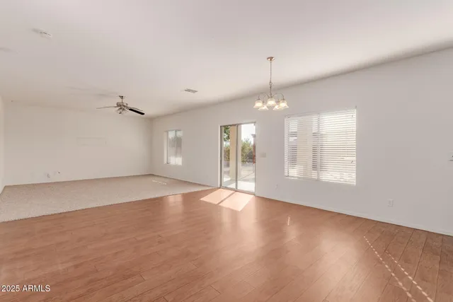 an empty room with chandelier fan and windows