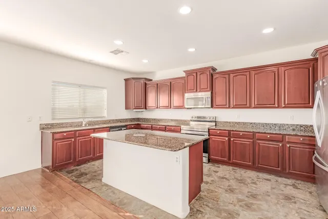 a kitchen with stainless steel appliances granite countertop a sink a stove and cabinets