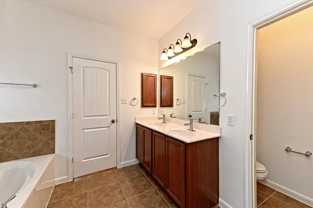 a spacious bathroom with a tub sink and mirror