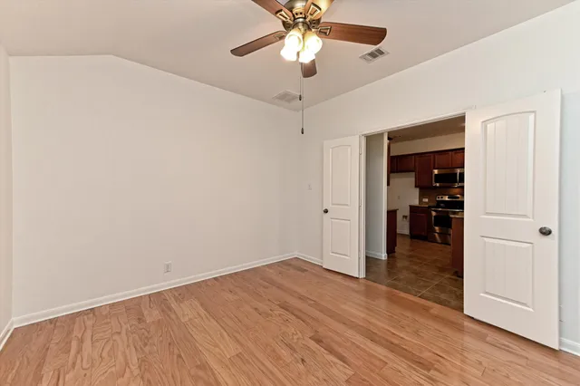 a view of an empty room with window and wooden floor