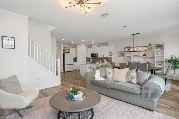 a living room with furniture kitchen view and a chandelier