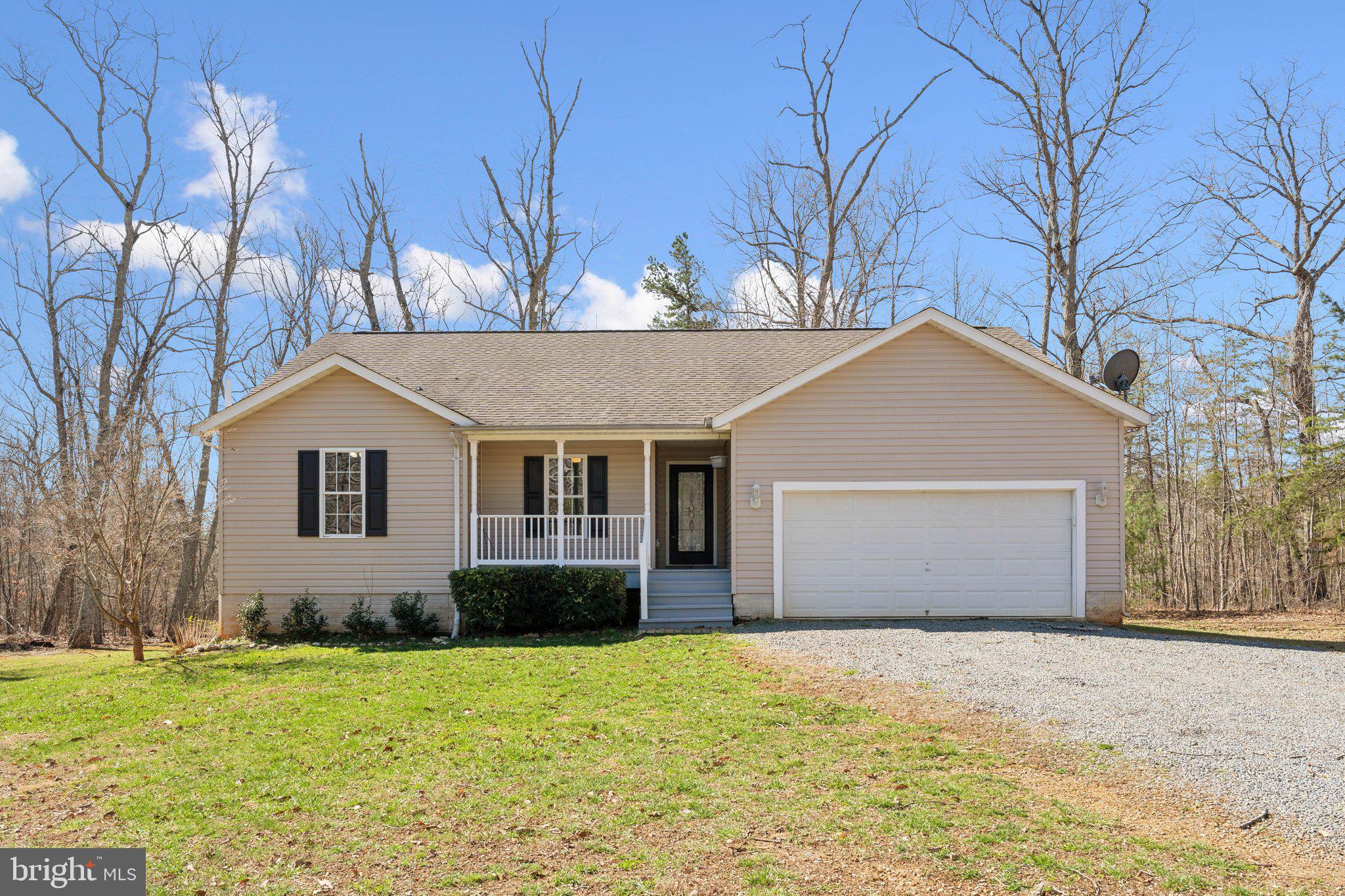 a front view of house with yard and trees in the background