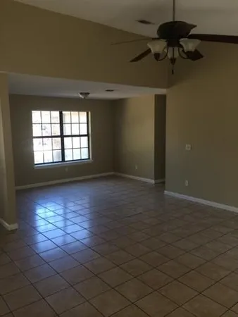 an empty room with windows and fan