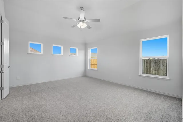 a view of an empty room with chandelier fan and a window