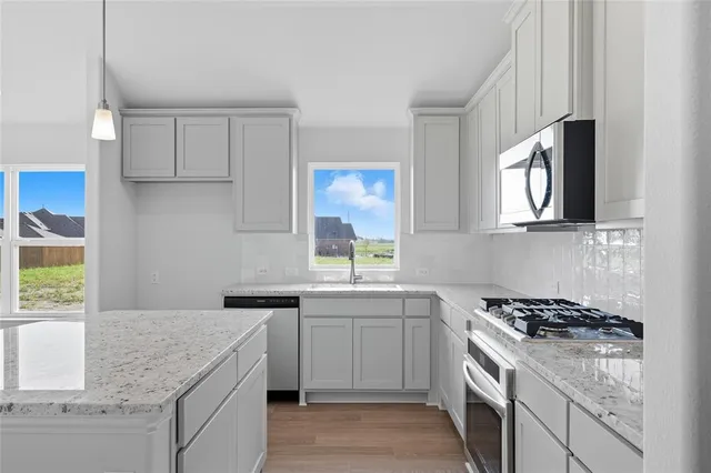 a kitchen with stainless steel appliances granite countertop a sink stove and refrigerator