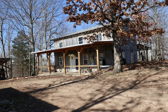 a front view of a house with yard and trees in the background