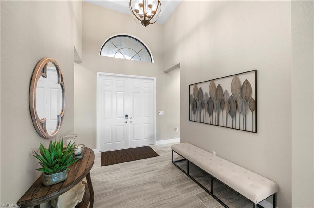 4365 Caldera Circle Naples, FL 34119 - Photo 16 of 23 Entryway featuring an inviting chandelier, light hardwood / wood-style flooring, and a towering ceiling