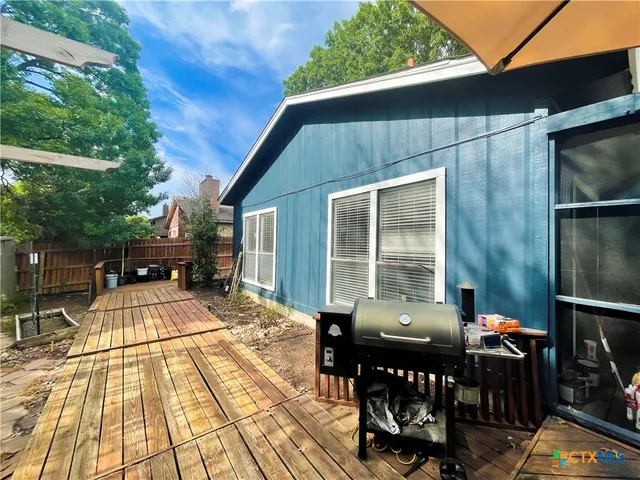 a view of a patio with table and chairs with wooden floor and fence