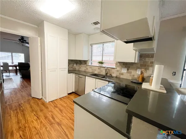 a kitchen with a sink a stove top oven a counter space and cabinets