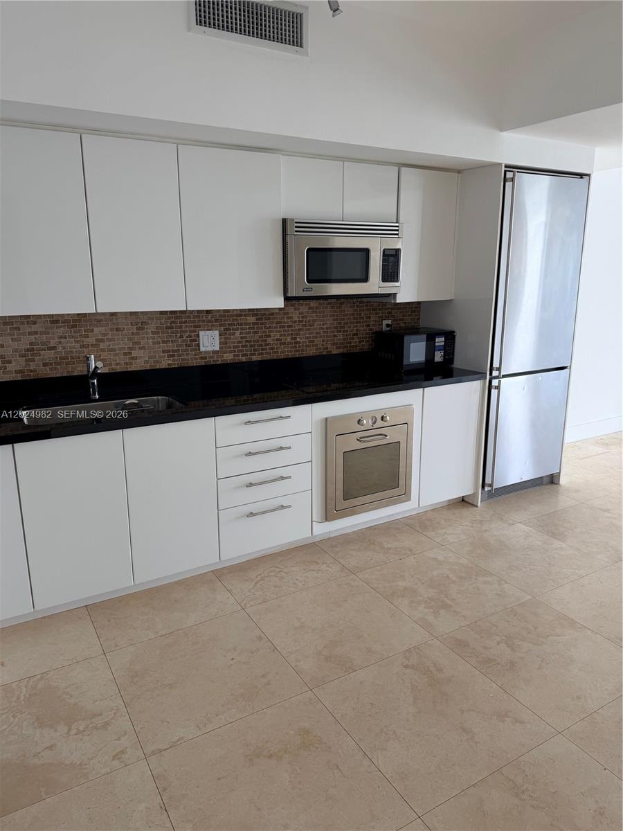 92 Southwest 3rd Street, Unit 3909 Miami, FL 33130 - Photo 11 of 13 a kitchen with granite countertop white cabinets and stainless steel appliances