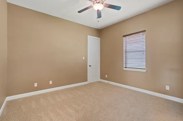 an empty room with a window and a ceiling fan