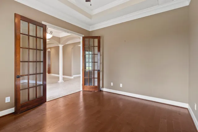 an empty room with wooden floor and windows with curtains