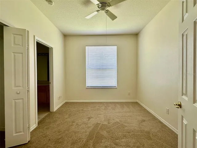 an empty room with a ceiling fan and window