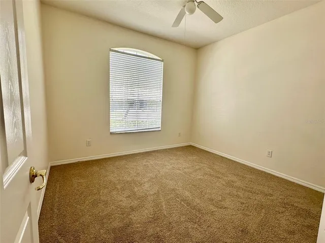 an empty room with a window and a ceiling fan