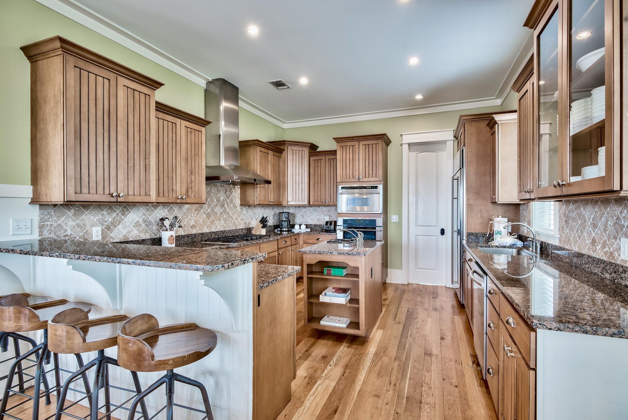 8045 East County Highway 30A Inlet Beach, FL 32461 - Photo 9 of 38 a kitchen with granite countertop wooden cabinets a stove a sink and a potted plant
