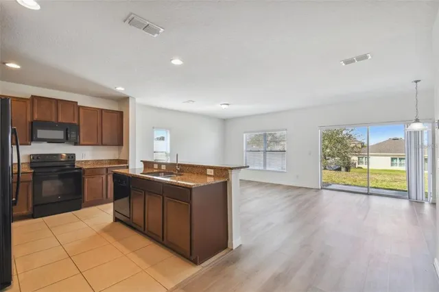 a large kitchen with stainless steel appliances granite countertop a refrigerator and a stove top oven