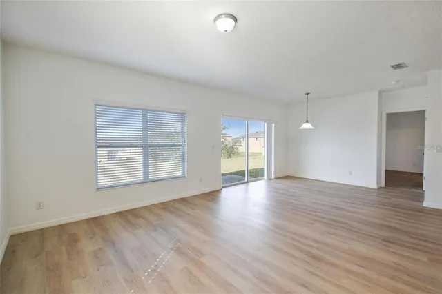 a view of an empty room with window and hardwood floor