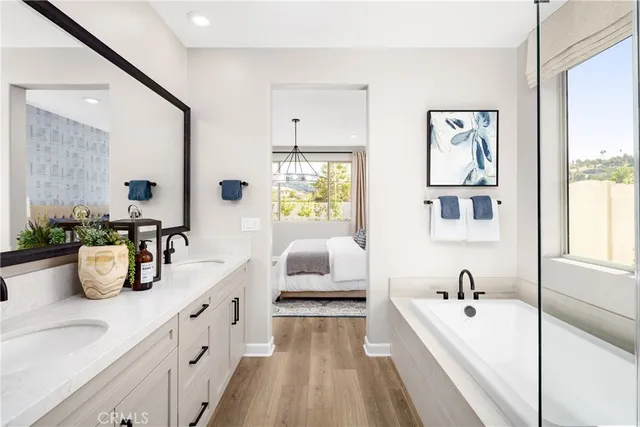 a bathroom with a tub a double vanity sink and mirror