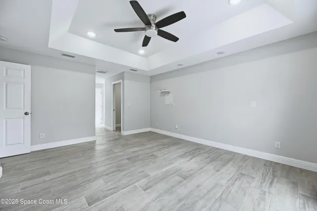 an empty room with wooden floor and ceiling fan