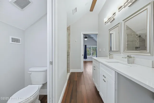 a bathroom with a sink a toilet a mirror and shower
