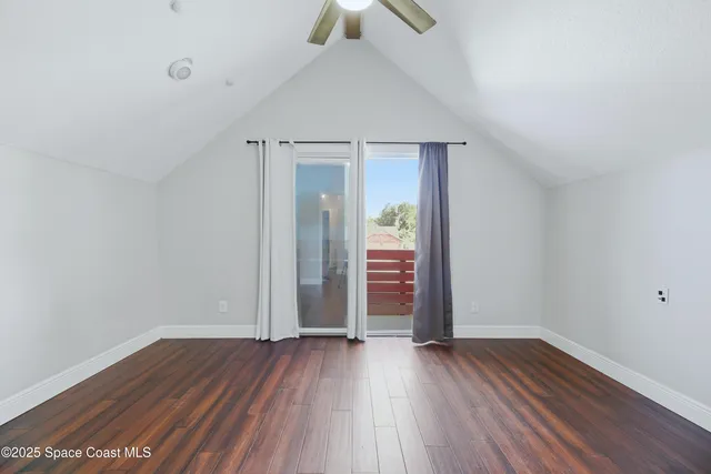 an empty room with wooden floor chandelier fan and windows
