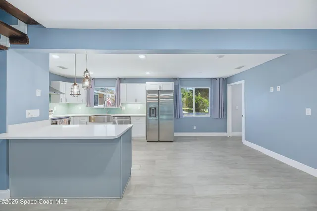 a view of a kitchen with kitchen island a sink wooden floor and counter top space