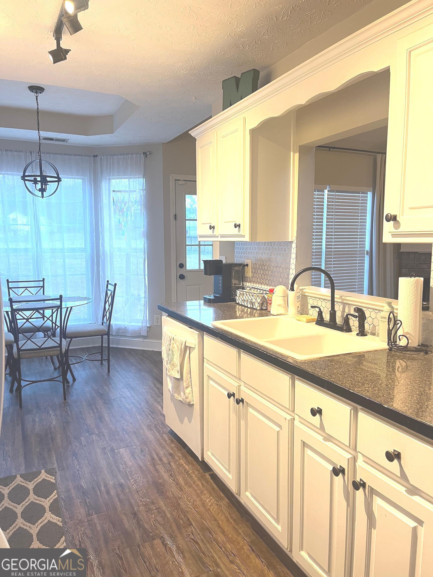 803 Lazy Lane Winder, GA 30680 - Photo 8 of 16 a large kitchen with kitchen island white cabinets and wooden floor