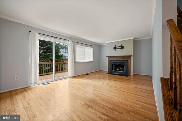 a view of an empty room with wooden floor fireplace and a window