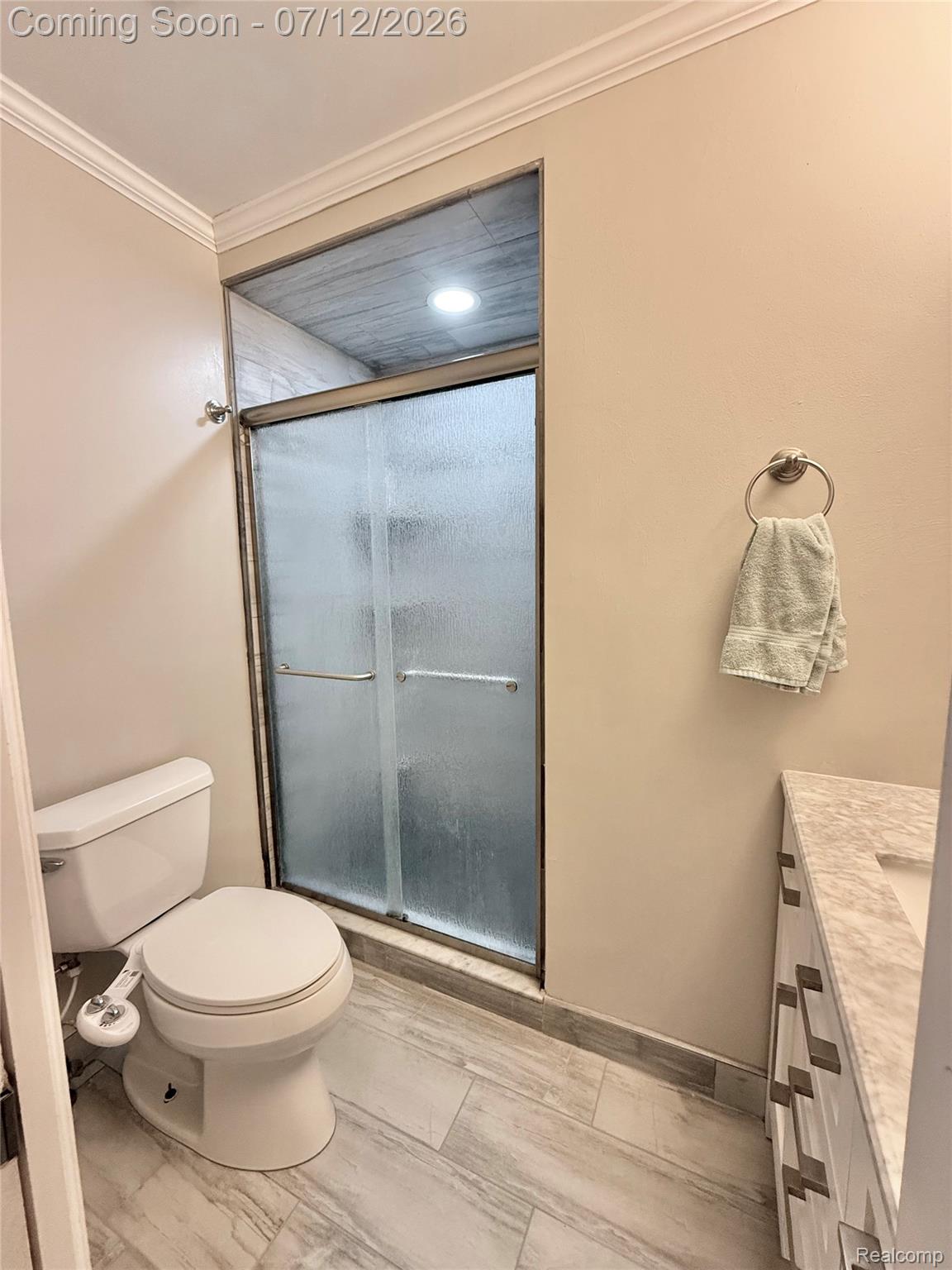 2033 Avonstoke Road Rochester, MI 48307 - Photo 10 of 26 Contemporary bathroom featuring a sliding glass shower door, light-toned wood-finish flooring, and a vanity with a light-colored countertop