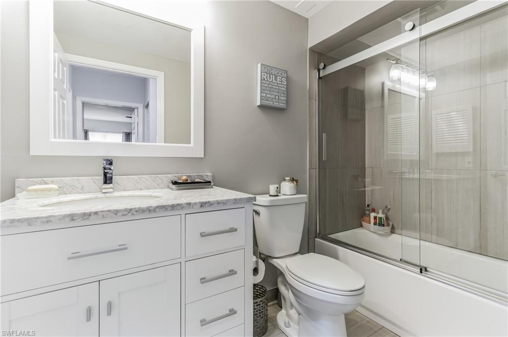 6895 Rain Lily Road, Unit 203 Naples, FL 34109 - Photo 14 of 22 a bathroom with a granite countertop toilet sink and mirror