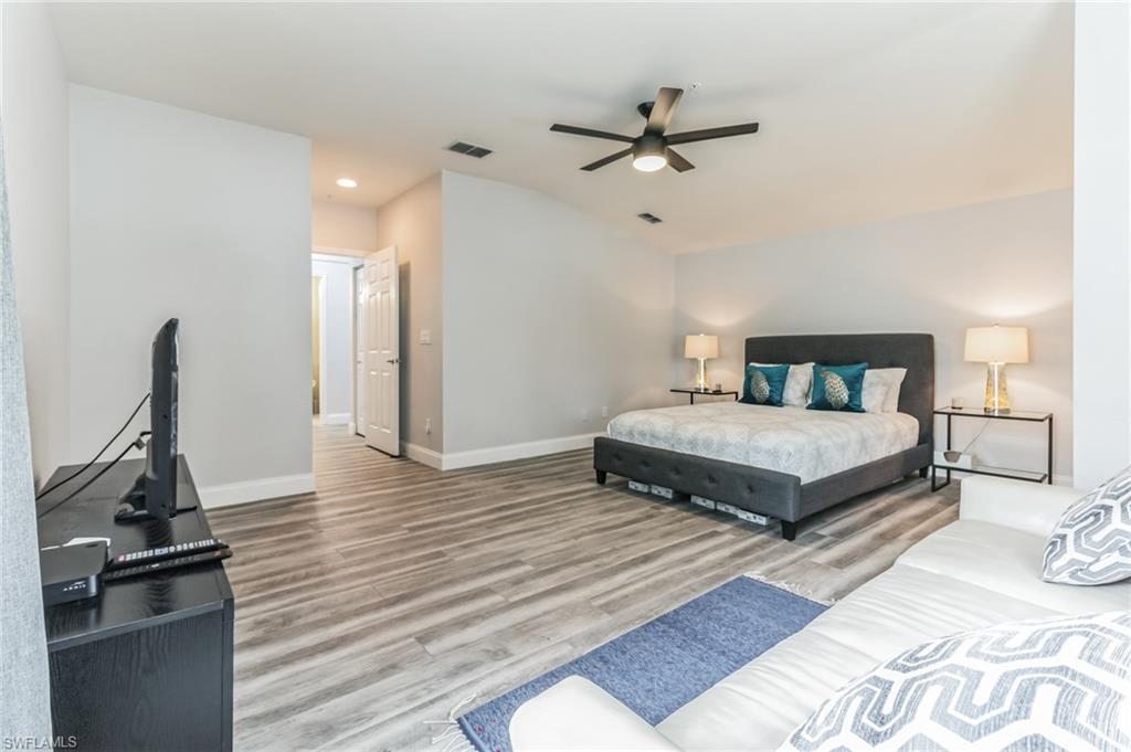 6895 Rain Lily Road, Unit 203 Naples, FL 34109 - Photo 16 of 22 a bedroom with a bed and wooden floor