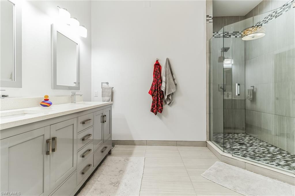 6895 Rain Lily Road, Unit 203 Naples, FL 34109 - Photo 17 of 22 a bathroom with a double vanity sink a toilet and shower