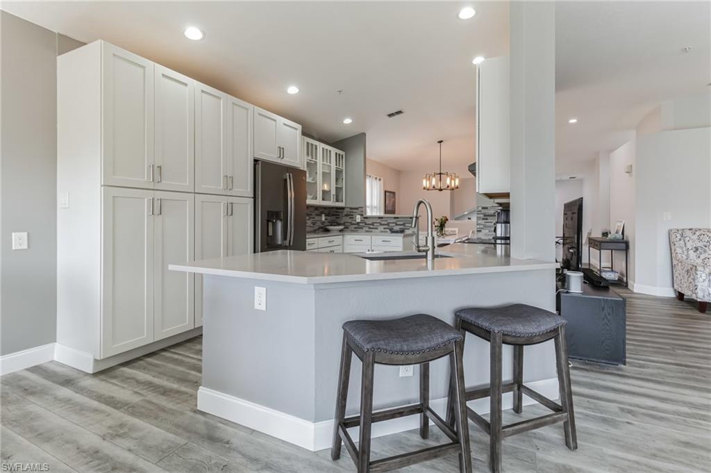 6895 Rain Lily Road, Unit 203 Naples, FL 34109 - Photo 5 of 22 a kitchen with white cabinets and stainless steel appliances