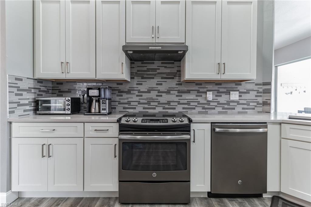 6895 Rain Lily Road, Unit 203 Naples, FL 34109 - Photo 7 of 22 a kitchen with granite countertop white cabinets and stainless steel appliances
