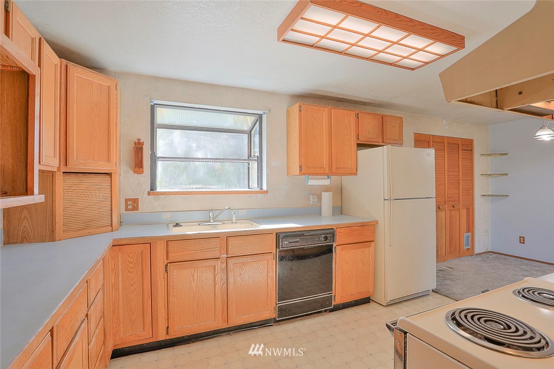 3601 Northeast 10th Street Renton, WA 98056 - Photo 9 of 25 a kitchen with stainless steel appliances granite countertop a refrigerator a sink dishwasher a stove with white cabinets and wooden floor