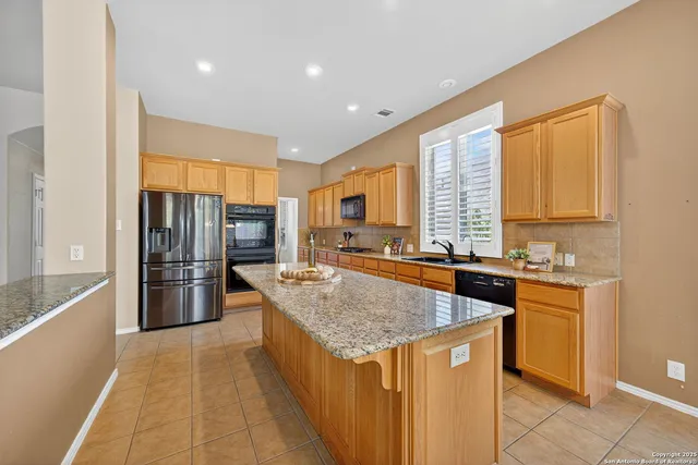 a kitchen with stainless steel appliances granite countertop a stove a refrigerator and a sink