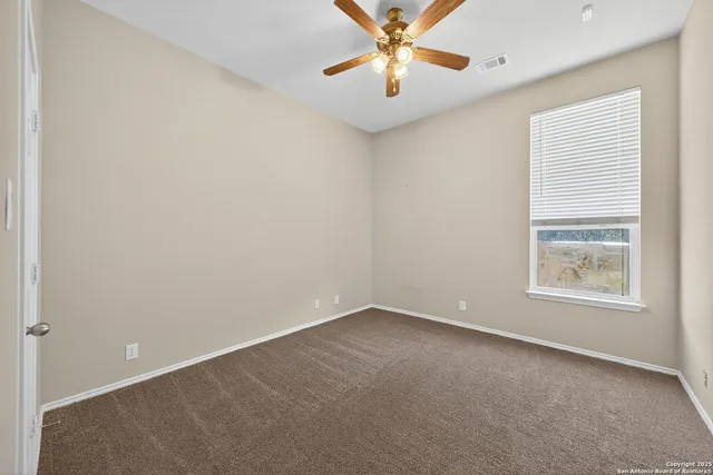 an empty room with windows and fan