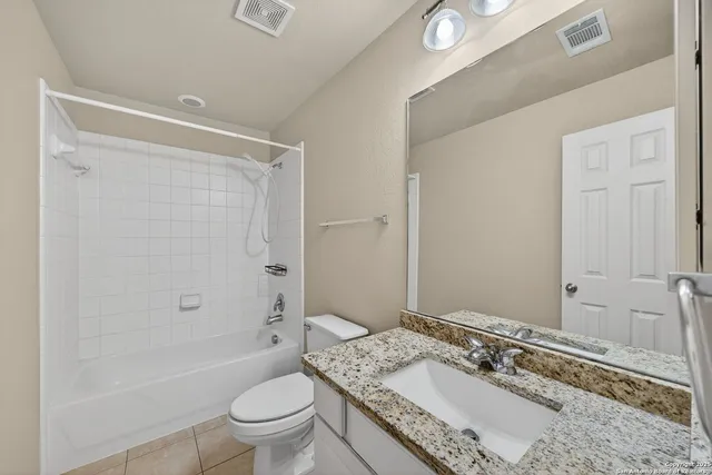 a bathroom with a granite countertop sink a toilet a mirror and shower