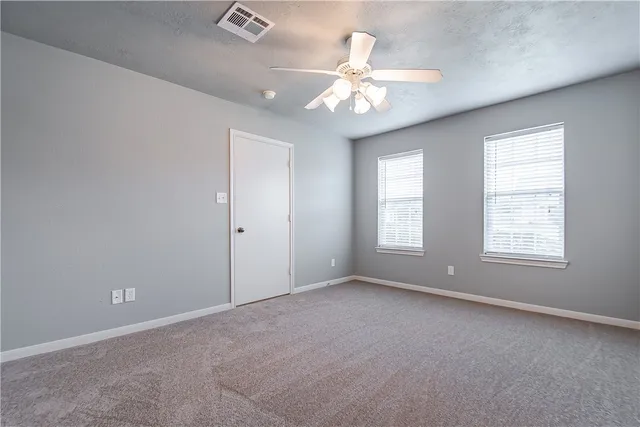 an empty room with windows and fan