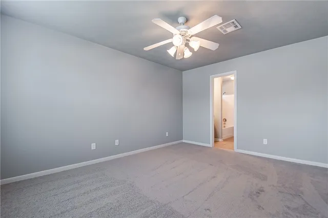 an empty room with a chandelier fan and windows