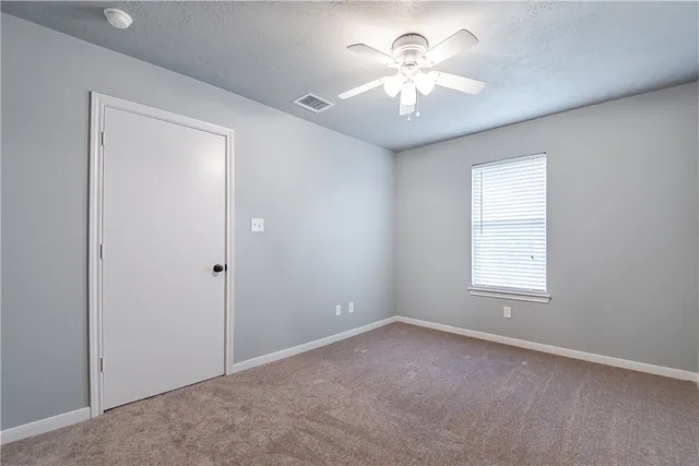 an empty room with chandelier fan and windows