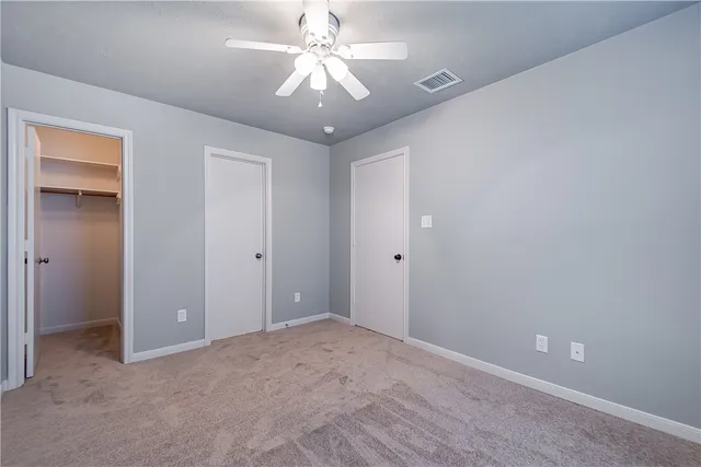 a view of an empty room and chandelier fan